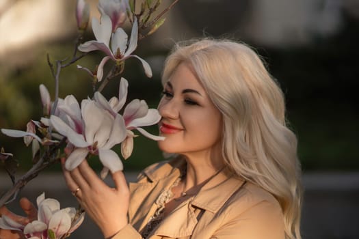 Magnolia flowers woman. A woman is holding a magnolia flower in her hand and standing in front of a tree. Concept of serenity and beauty, as the woman is surrounded by nature and the flower adds a touch of color