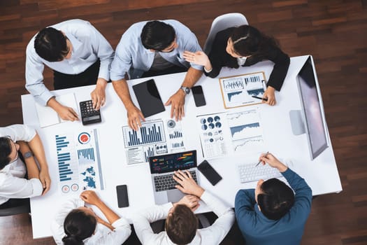 Top view analyst team utilizing BI Fintech to analyze financial data at table in meeting room. Analytic BI dashboard power on paper for business insight and strategic marketing planning. Prudent