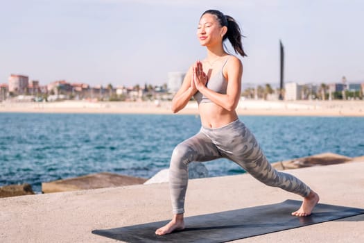 young asian woman in sportswear practicing yoga by the sea, relaxation and healthy lifestyle concept