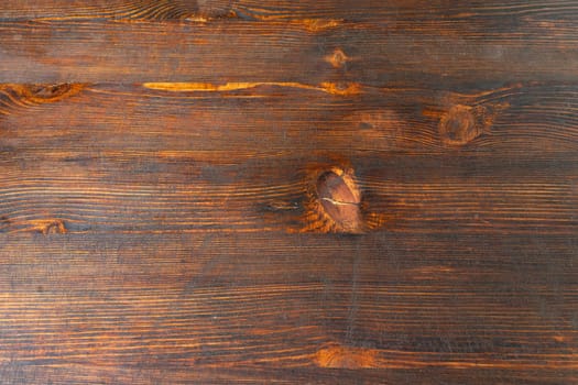 A closeup of a brown hardwood plank with a beautiful knot in the amber wood. The natural grain and shading make it a perfect choice for flooring with wood stain and varnish