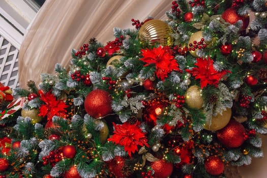 A festive closeup of an evergreen Christmas tree adorned with red and gold ornaments, creating a beautiful holiday display