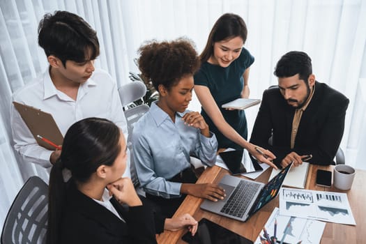 Multiracial analyst team use BI dashboard data to analyze financial report on meeting table. Group of diverse business people utilize data analysis by FIntech for success business marketing. Concord