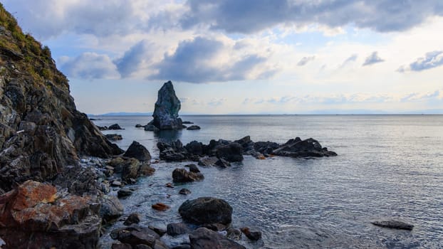 Sacred Kamitate Gamiiwa coastal rock formation with calm sea and horizon on cloudy morning. High quality photo