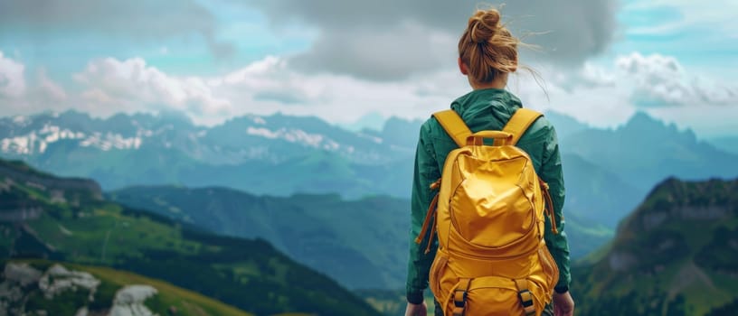 A woman is standing on a mountain top with a yellow backpack on.