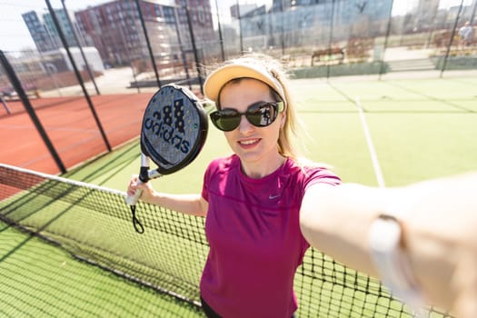 Ukraine Kyiv, March 31 2024. A girl in sportswear is training on a paddle tennis court. Concept of women playing paddle. High quality photo