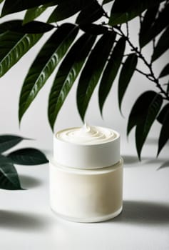 The image is a white jar of cream sitting on a green leaf.