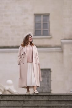woman in elegant coat and hat against an intricate architectural backdrop, harmoniously blending modern fashion with historical allure. The soft daylight adds to its timeless appeal