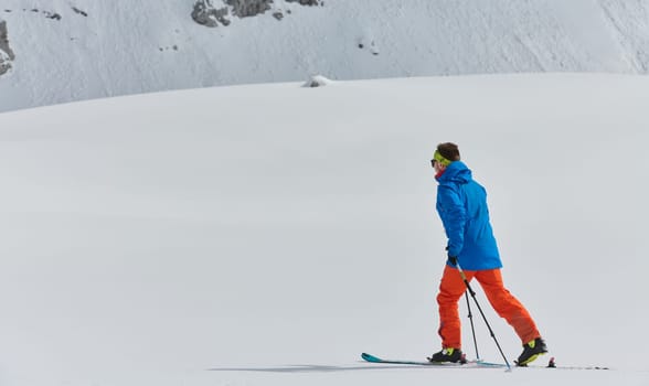 A lone skier braves the elements on a perilous climb to the top of an alpine peak.