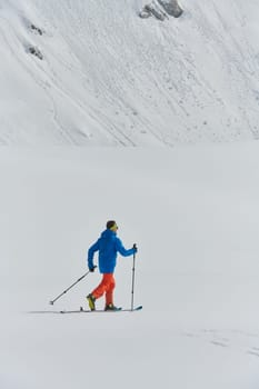 A lone skier braves the elements on a perilous climb to the top of an alpine peak.