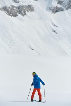 A lone skier braves the elements on a perilous climb to the top of an alpine peak.