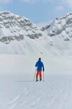 A lone skier braves the elements on a perilous climb to the top of an alpine peak.