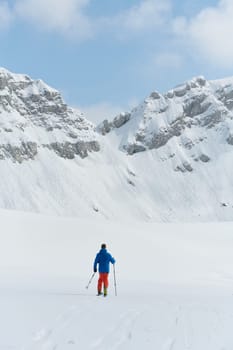 A lone skier braves the elements on a perilous climb to the top of an alpine peak.