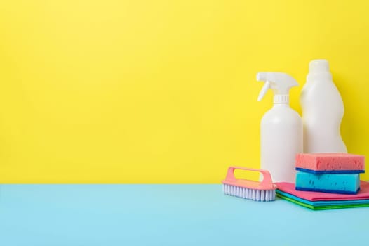House cleaning products on yellow blue background, copy space. Cleaning service or housekeeping concept with space for text or design