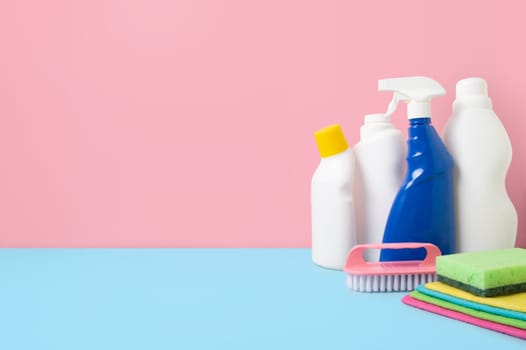 House cleaning products on blue pink background, copy space. Cleaning service or housekeeping concept with space for text or design