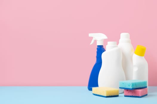 House cleaning products on blue pink background, copy space. Cleaning service or housekeeping concept with space for text or design