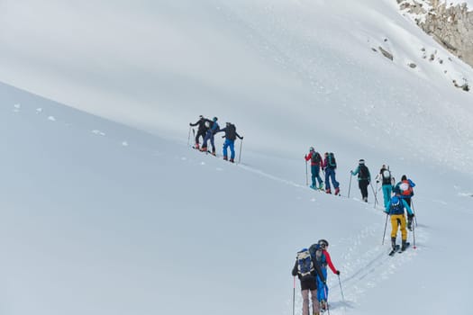 A group of professional ski mountaineers ascend a dangerous snowy peak using state-of-the-art equipment.