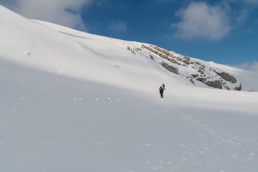 A group of professional ski mountaineers ascend a dangerous snowy peak using state-of-the-art equipment.