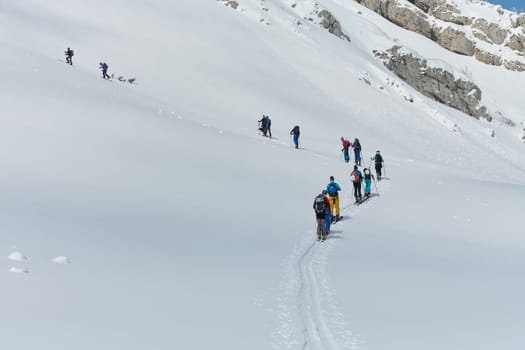 A group of professional ski mountaineers ascend a dangerous snowy peak using state-of-the-art equipment.