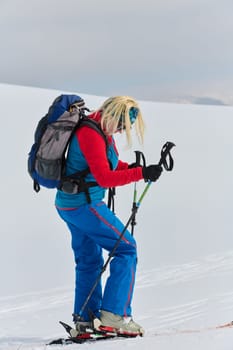 A determined skier scales a snow-capped peak in the Alps, carrying backcountry gear for an epic descent