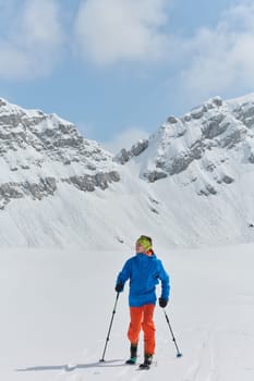 A lone skier braves the elements on a perilous climb to the top of an alpine peak.