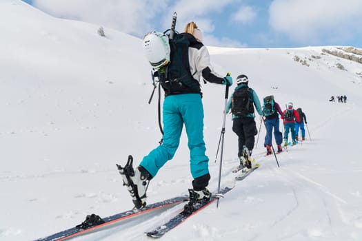 A group of professional ski mountaineers ascend a dangerous snowy peak using state-of-the-art equipment.
