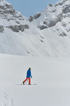 A lone skier braves the elements on a perilous climb to the top of an alpine peak.