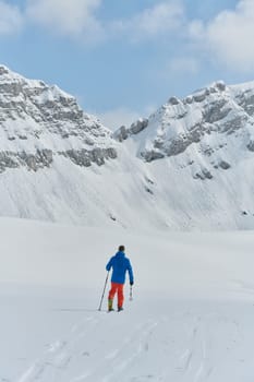 A lone skier braves the elements on a perilous climb to the top of an alpine peak.