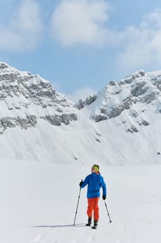 A lone skier braves the elements on a perilous climb to the top of an alpine peak.