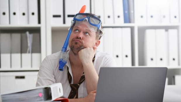 Man wearing suit and tie in goggles with snorkel sit at office workplace ready to take off portrait. Count days to leave annual day off workaholic freedom fun tourism resort idea concept