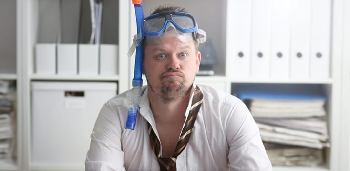 Man wearing suit and tie in goggles with snorkel sit at office workplace ready to take off portrait. Count days to leave annual day off workaholic freedom fun tourism resort idea concept