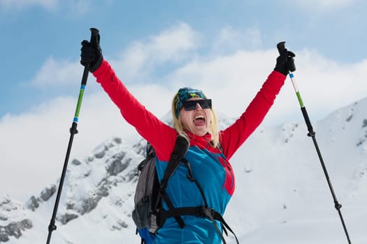 A professional woman skier rejoices after successfully climbing the snowy peaks of the Alps.