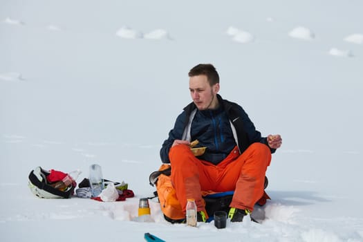 A skier pauses on a snow-capped ridge to savor a moment of peace and take in the breathtaking alpine panorama.