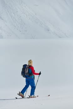 A determined skier scales a snow-capped peak in the Alps, carrying backcountry gear for an epic descent