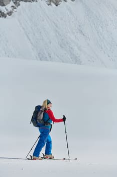 A determined skier scales a snow-capped peak in the Alps, carrying backcountry gear for an epic descent