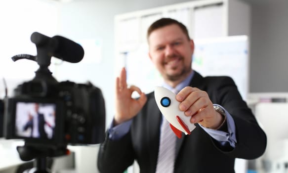 Businessman hold rocket in hand closeup on office background business concept