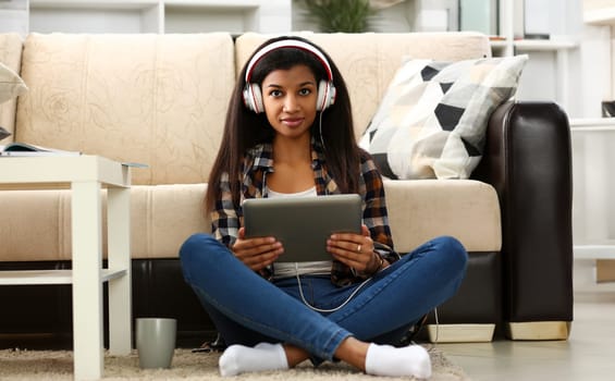 Black ordinary female american teen portrait at home sofa remote education concept. Girl hold tablet in hand music apps teacher checks homework online university library learning foreign languages