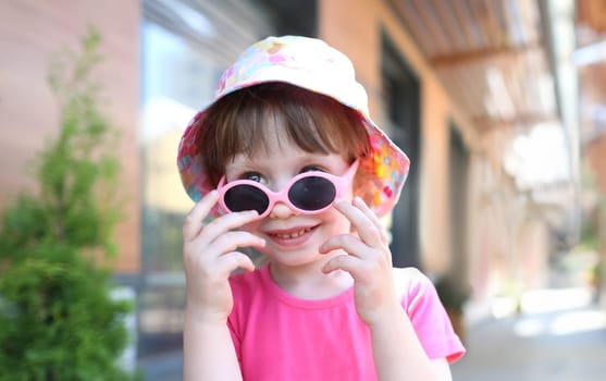 Happy smiling girl child in sunglasses outdoor portrait. Childhood concept.