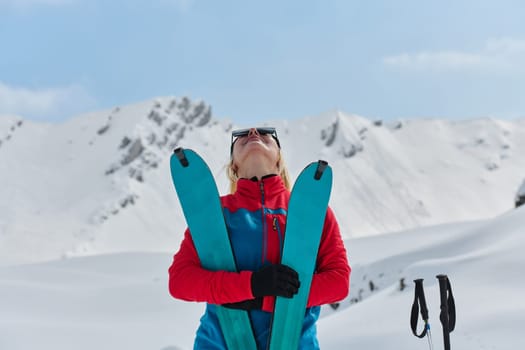 A professional woman skier rejoices after successfully climbing the snowy peaks of the Alps.