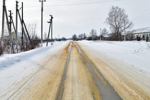 Rural winter a oad sprinkled with sand against ice