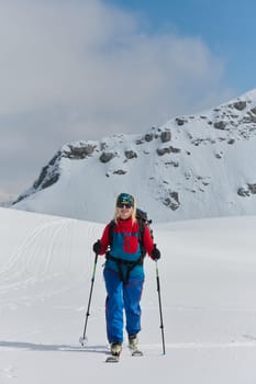 A professional woman skier rejoices after successfully climbing the snowy peaks of the Alps.