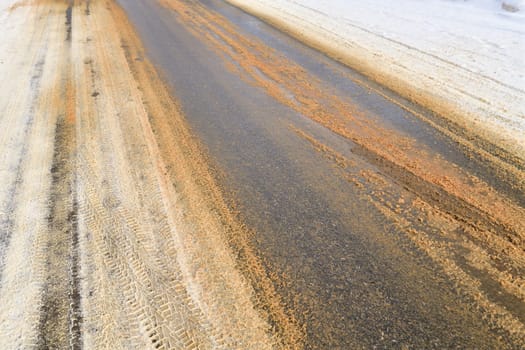 Rural winter a oad sprinkled with sand against ice