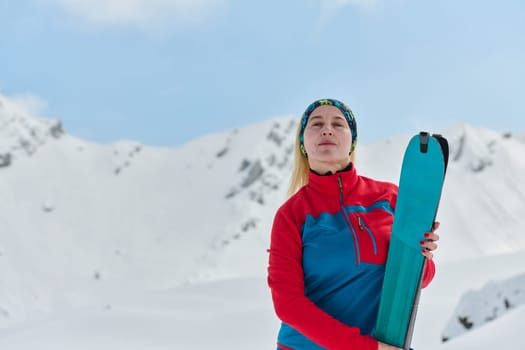 A triumphant female skier beams with confidence atop a snow-capped peak after conquering a challenging ascent.