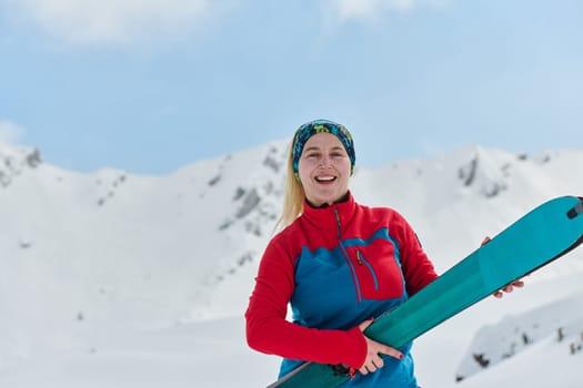 A triumphant female skier beams with confidence atop a snow-capped peak after conquering a challenging ascent.