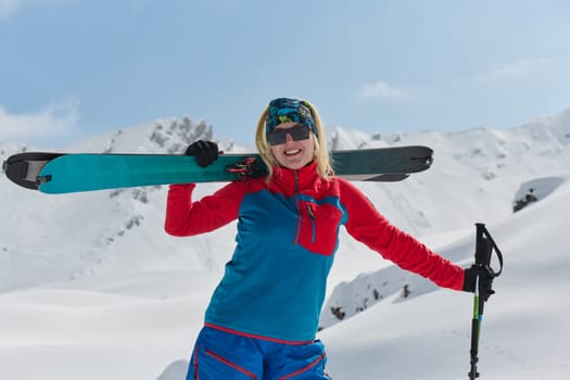 A professional woman skier rejoices after successfully climbing the snowy peaks of the Alps.