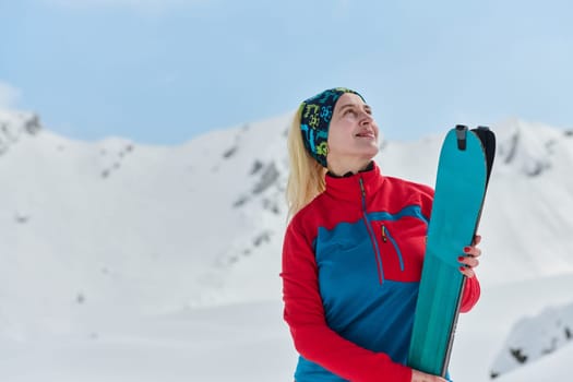 A triumphant female skier beams with confidence atop a snow-capped peak after conquering a challenging ascent.