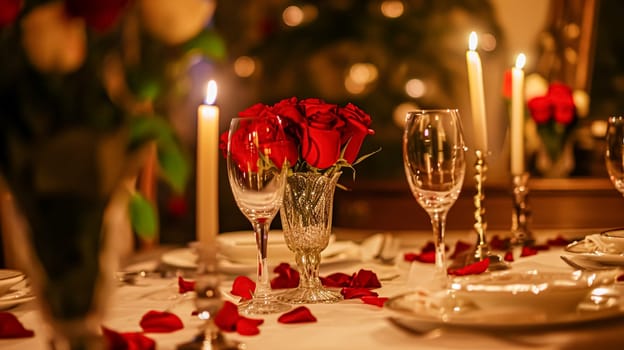 Festive table setting with cutlery, candles and beautiful red flowers in a vase.