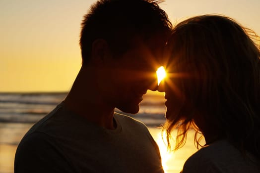 Couple, love and kiss at beach with silhouette for date or summer holiday and bonding in Florida. Relationship, commitment and romance together as soulmate with smile, vacation and honeymoon sunset.