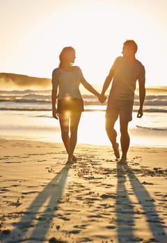 Lens flare, sunset and couple holding hands at beach, ocean and sea with affection, bonding and love. People, partners and romance for care together on vacation, holiday and travel in Australia.