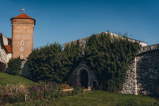 Stone tower and wall, green garden of Wawel Royal Castle complex in Krakow, Poland