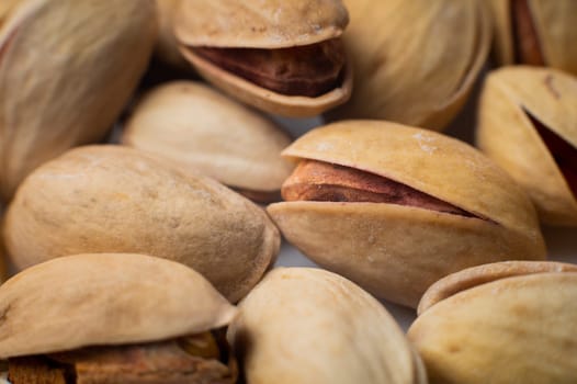 Many closed pistachios in macro close-up. Healthy food background with selective soft focus.